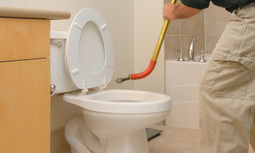 Un plombier debouche une toilette avec un furet de debouchage professionnel